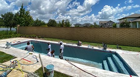 A few men inside a swimming pool installing a new pool