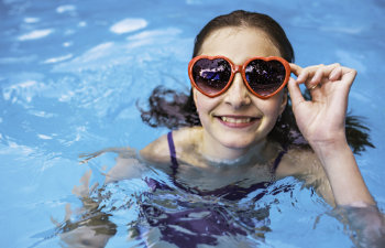 girl having fun on pool with heart glasses on the summer time