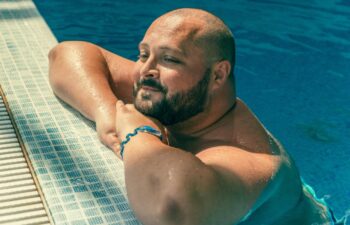 Portrait of plus size big happy smiling man relaxing in swimming pool