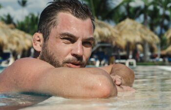 Handsome wrestler sportsman with Cauliflower ears relaxes in the swimming pool, recovery after hard training.